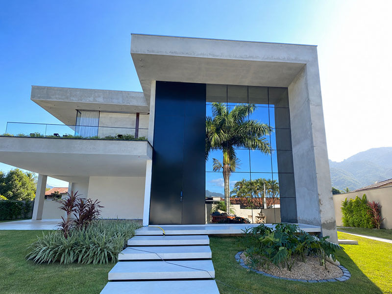 Porta metálica pivotante de grandes dimensões instalada na entrada de casa de alto padrão em Joinville